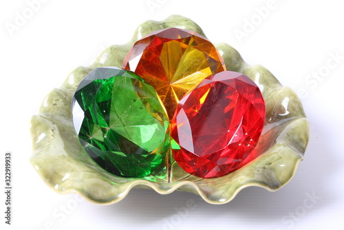 Colored assorted gemstones in  green bowl on a white background