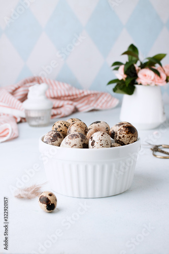 Easter spring decorative composition with homemade easter quail eggs and roses. On a white and blue background. Holiday celebration decorations. Happy Easter. Congratulatory easter background. photo