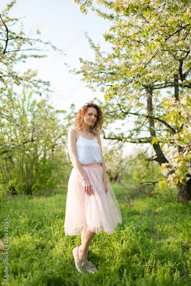 Young attractive girl walks in spring green park enjoying flowering nature. Healthy smiling girl spinning on the spring lawn. Allergy without Young attractive girl walks in spring green park enjoying flowering nature. Healthy smiling girl spinning on the spring lawn. Allergy without