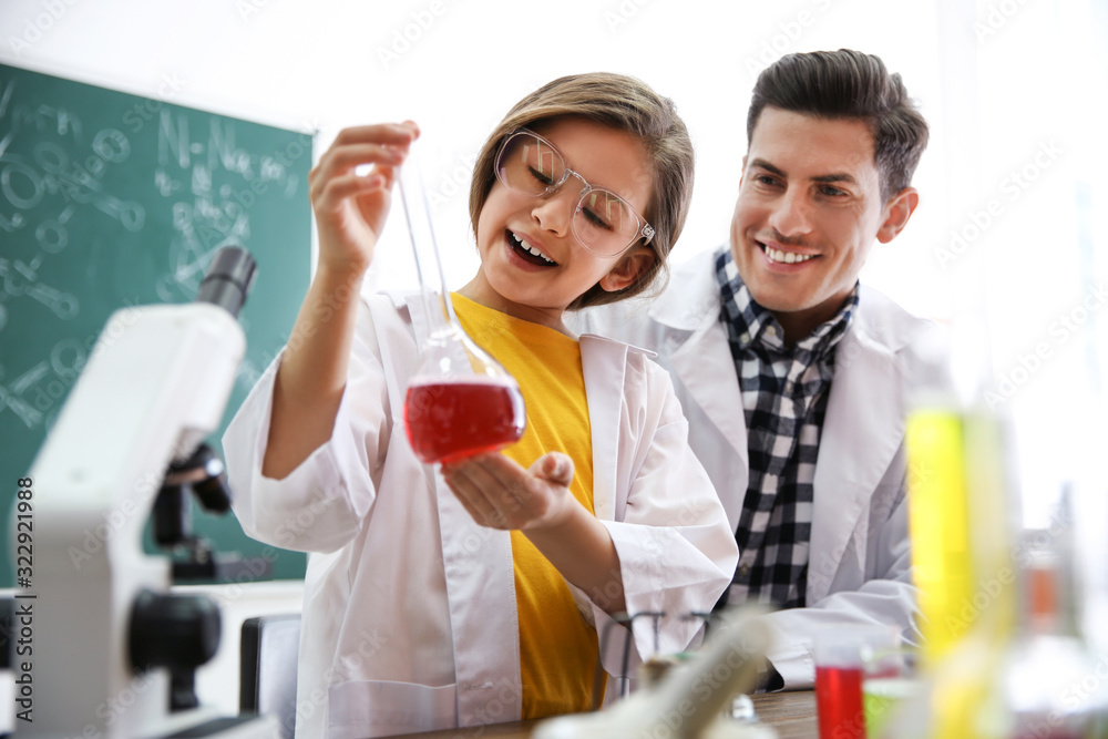 Teacher with pupil making experiment in chemistry class Teacher with pupil making experiment in chemistry class