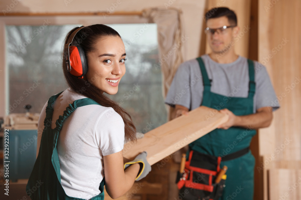 Professional carpenters with wooden plank in workshop Professional carpenters with wooden plank in workshop