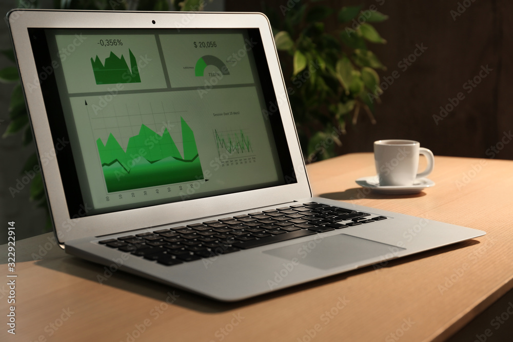 Modern laptop and cup of coffee on desk in office Modern laptop and cup of coffee on desk in office
