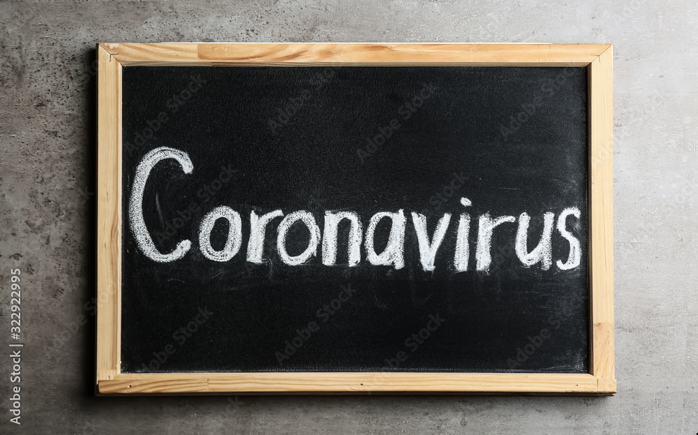 Fototapeta premium Blackboard with word CORONAVIRUS on light grey stone table, top view