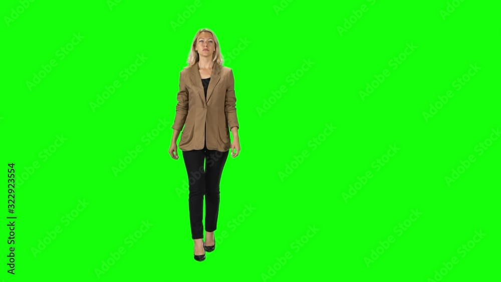 Blonde girl in a stylish brown jacket, black trousers and high-heeled shoes going against a green screen. Blonde girl in a stylish brown jacket, black trousers and high-heeled shoes going against a green screen.