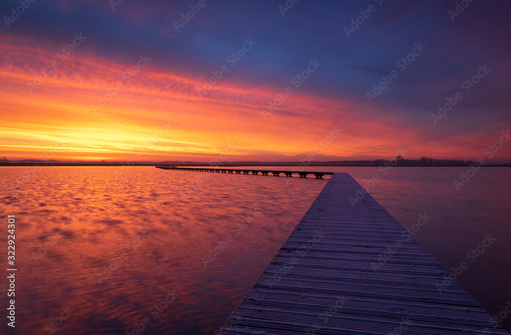 Very colorful and tranquil dawn at a jetty in a lake. Groningen, Holland.