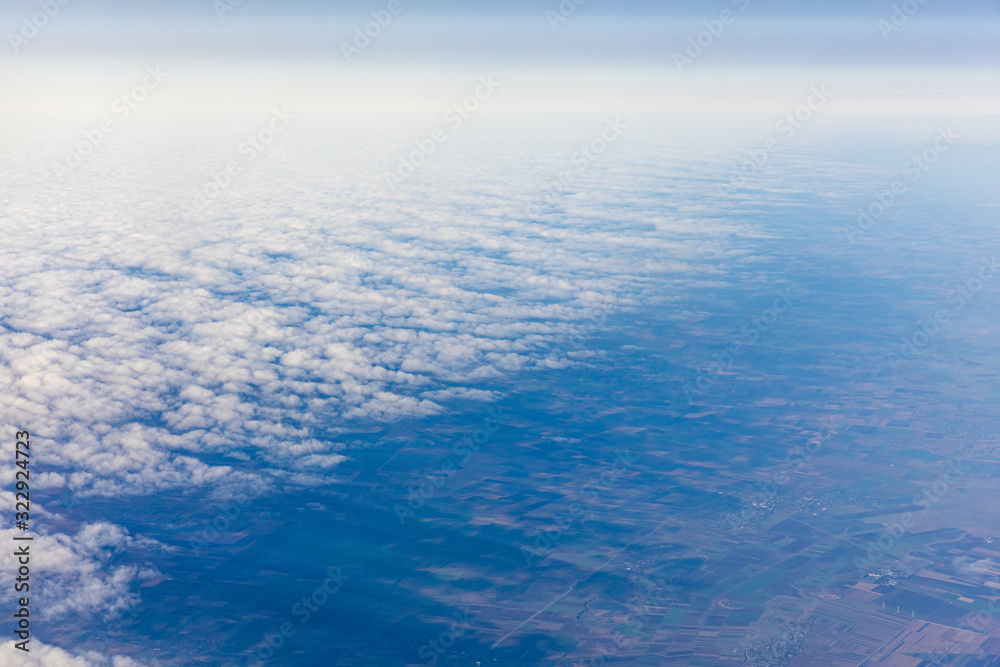 Aerial view of fluffy clouds through an airplane window Aerial view of fluffy clouds through an airplane window