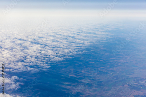 Aerial view of fluffy clouds through an airplane window