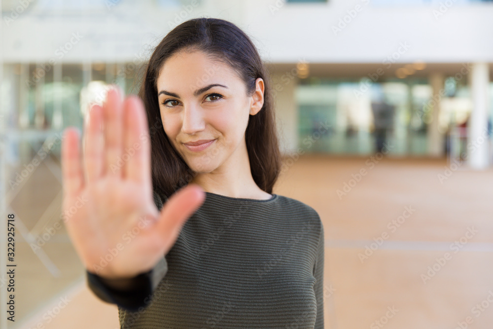 Smiling young woman showing stop gesture. Beautiful lady with outstretched arm. Warning or prohibition concept Smiling young woman showing stop gesture. Beautiful lady with outstretched arm. Warning or prohibition concept