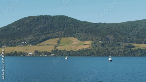 Loch ness in Scotland. Boats cruise on the water with rolling hills in the background photo