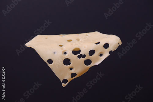 Slice of cheese isolated on a black background. Copy space. Ingridients for making a hamburger. photo