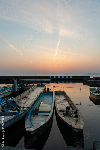 夜明けのオレンジ色の空と琵琶湖と漁船と飛行機雲 © sigmaphoto