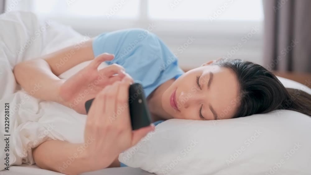 beautiful girl spends time on the phone while lying in bed beautiful girl spends time on the phone while lying in bed