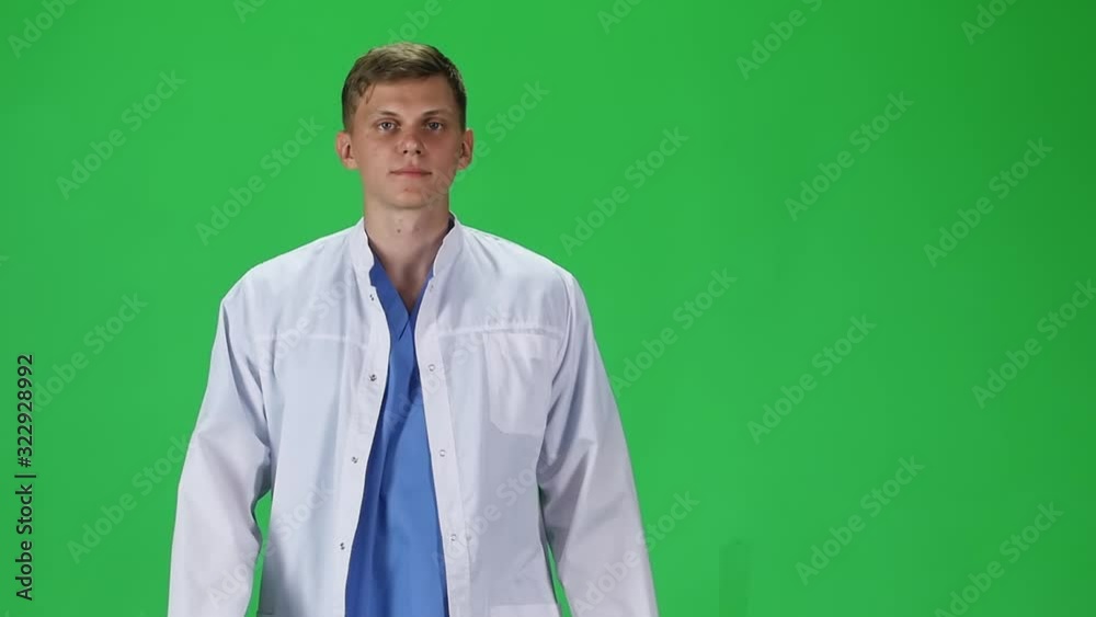 Medical man in white coat going and looking forward against a green background. Slow motion. Medical man in white coat going and looking forward against a green background. Slow motion.