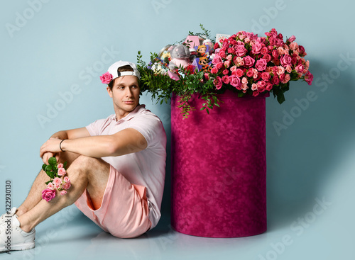 Fotografija Man in sneakers shorts t-shirt is sitting with bouquet of flowers in his hand at