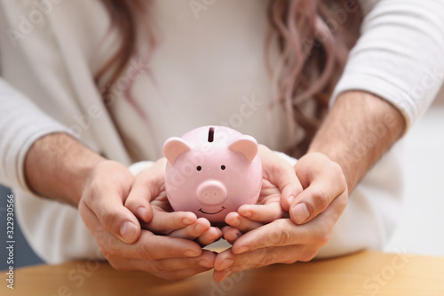 Couple holding piggy bank at table, closeup