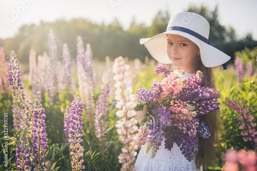Beautiful girl in a white dress and hat in a field of flowers