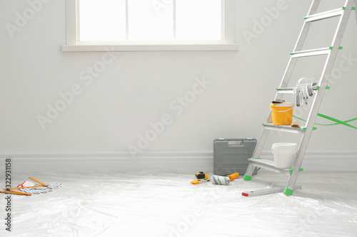 Stepladder and different tools near wall in room. Interior renovation