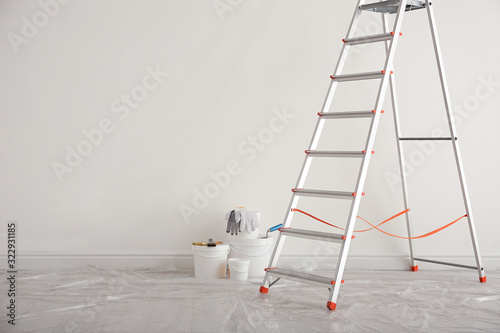 Stepladder and different tools near wall in room, space for text. Interior renovation