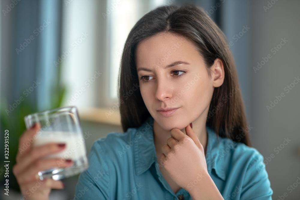 Thoughtful woman looking at the glass of milk Thoughtful woman looking at the glass of milk
