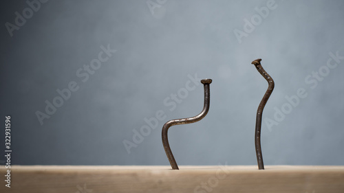 Two bent nails driven into a board. Concept stoop, sciatica and degenerative disc disease photo