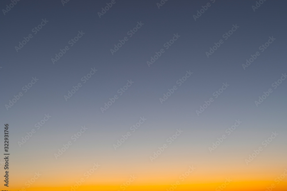 Heaven at early morning with copy space. Smooth orange blue gradient of dawn sky.Sunset, sunrise backdrop.Predawn clear sky with orange horizon and blue atmosphere.  Background of beginning of day.