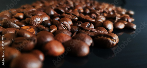 Roasted coffee beans on black glass background