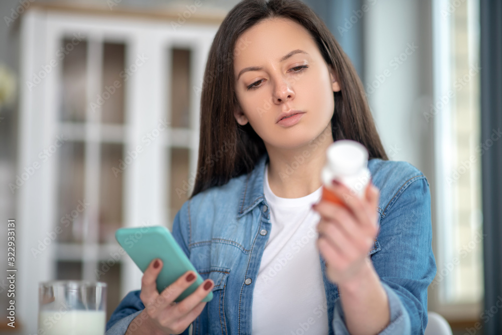 Woman looking for the instruction for drugs using her smartphone Woman looking for the instruction for drugs using her smartphone