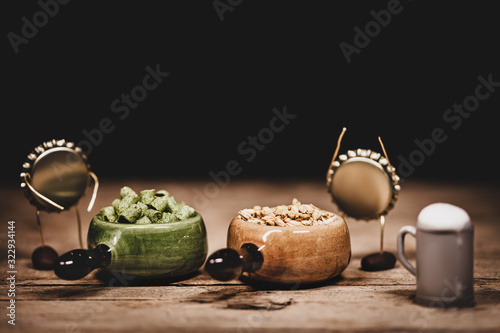 Crown cork miniature figures with hop pellets, barley and beer jug, concept ngredients for brewing beer and a brewery photo