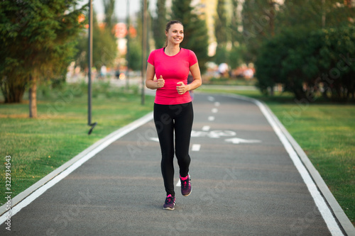 beautiful young woman runs in summer park on a treadmill © Alexandr