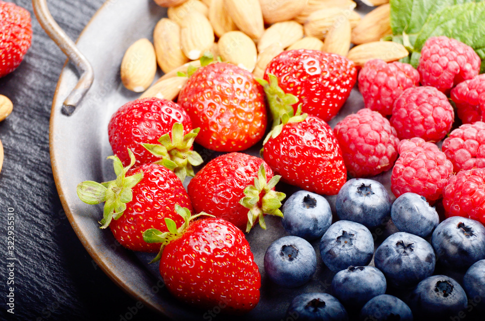 Tray with ripe organic bilberry raspberry strawberry and almonds set on slate closeup Tray with ripe organic bilberry raspberry strawberry and almonds set on slate closeup