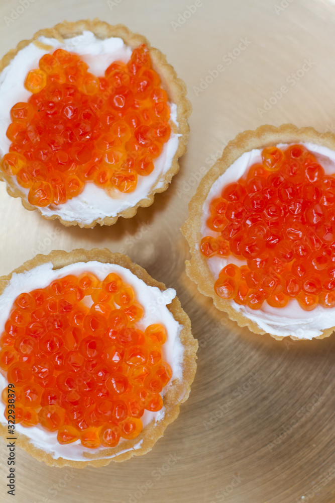 three tartlets with cream cheese and red caviar on a white background. the concept of a delicious Breakfast, buffet and snack. seafood dish. the view from the top. space for text. three tartlets with cream cheese and red caviar on a white background. the concept of a delicious Breakfast, buffet and snack. seafood dish. the view from the top. space for text.
