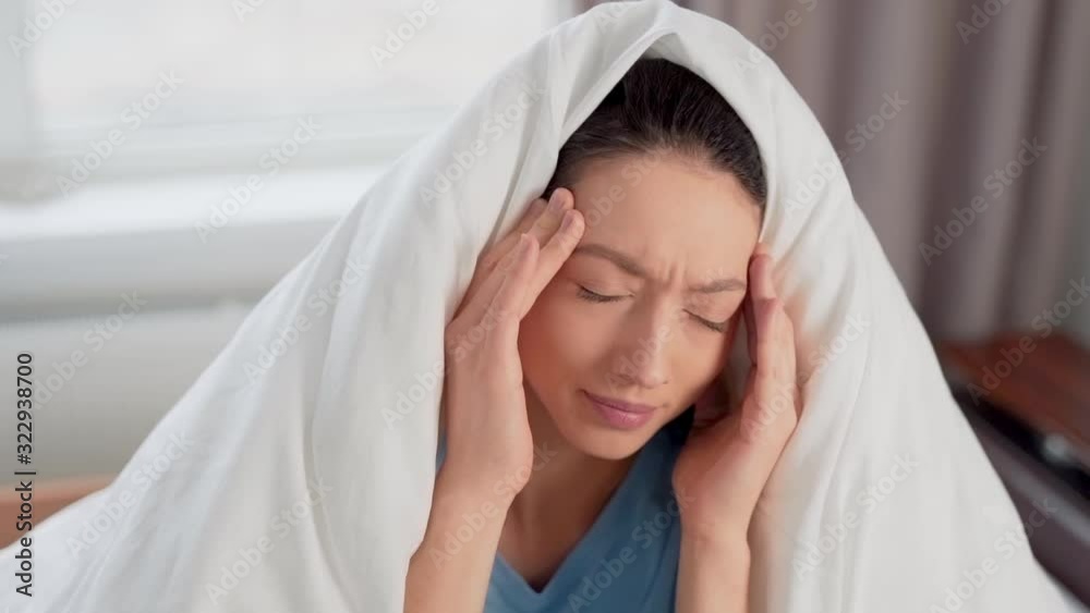 pretty girl suffering from headache while sitting on bed pretty girl suffering from headache while sitting on bed