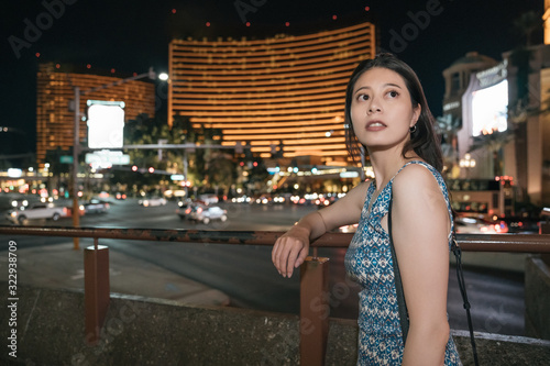 Photography side view of beautiful asian woman traveler standing leaning on railing with bokeh background of famous luxury five star hotel in las vegas