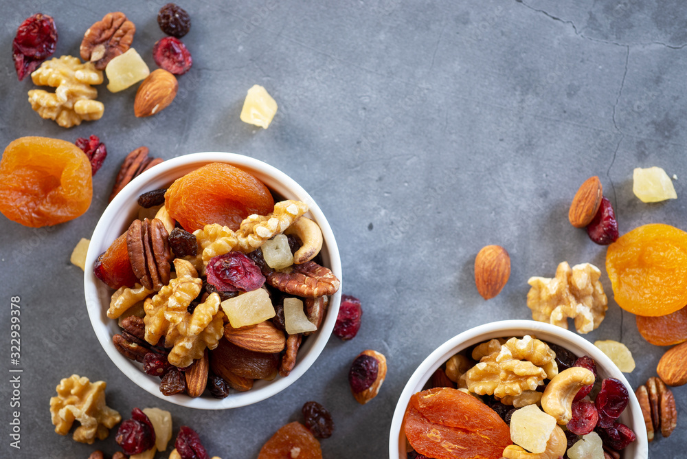 Φωτογραφία healthy snack: mixed nuts and dried fruits in white ceramic bowl on dark cement table background, almond, pineapple, cranberry, papaya, apple, strawberry, cherry, apricot, cashew