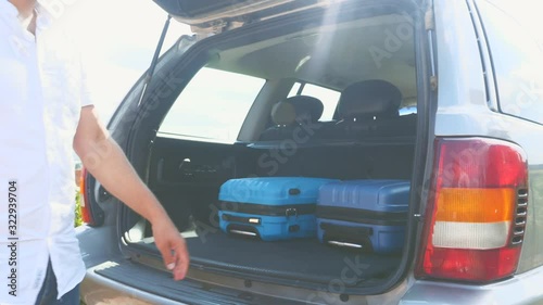 Happy man and woman put suitcases into the car boot. Close up. Copy space. 4K.