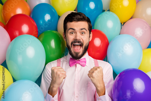 Photo of funny handsome guy colorful decorations ready birthday party festive mood raise fists meet guests wear pink shirt bow tie suspenders on balloons creative design background © deagreez