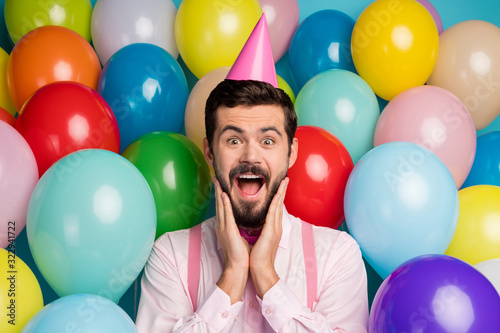 Photo of funny gentleman guy colorful balloons everywhere arrange birthday party not believe eyes wear paper cone cap pink shirt bow tie suspenders on balloons creative background
