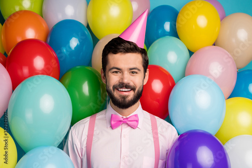 Photo of funny gentleman guy surrounded colorful balloons arranging birthday party wear paper cone cap pink shirt bow tie suspenders on bright many balloons design background © deagreez