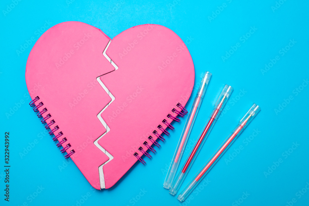 broken heart notebook on blue paper background broken heart notebook on blue paper background