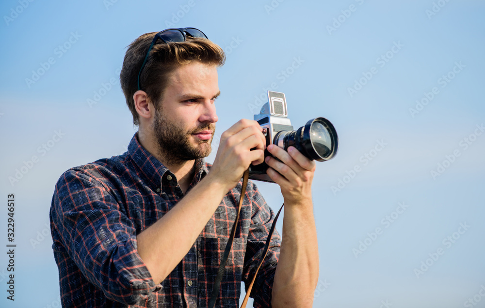 Guy outdoors blue sky background. Photojournalist concept. Travel blogger. Reporter taking photo. Vintage equipment. Blogger shooting vlog. Vacation time. Handsome blogger guy traveler retro camera
