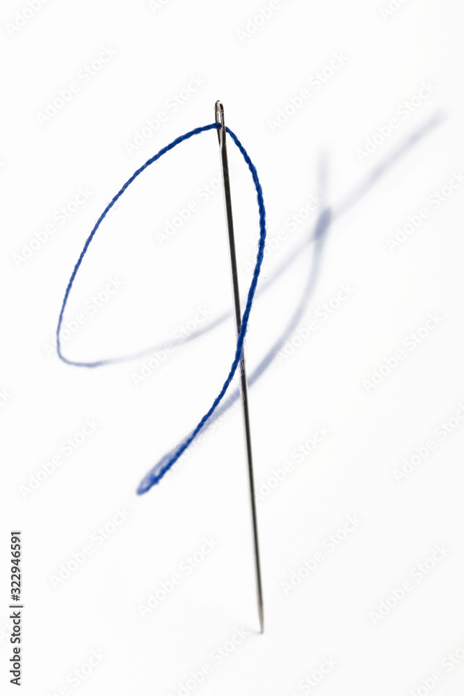 Sewing needle with blue thread on the white background Sewing needle with blue thread on the white background