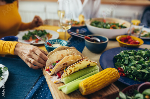 close up of caucasian mixed aged family and friends having vegetarian dinner party at home photo