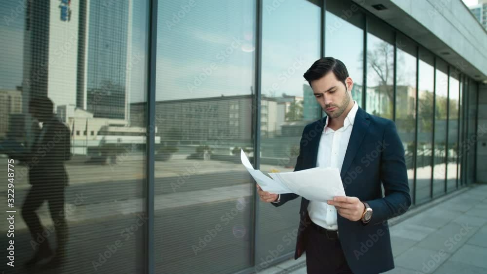 Closeup man walking with papers at street. Businessman reading documents outdoor Closeup man walking with papers at street. Businessman reading documents outdoor
