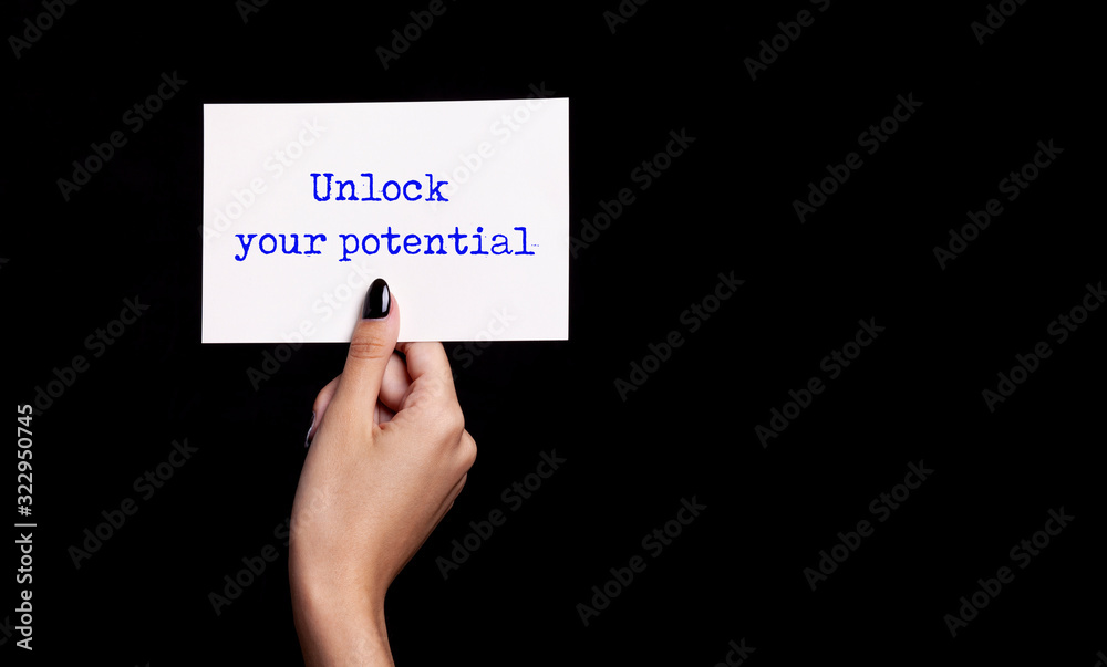 hand holding white card on black background - unlock your potential hand holding white card on black background - unlock your potential