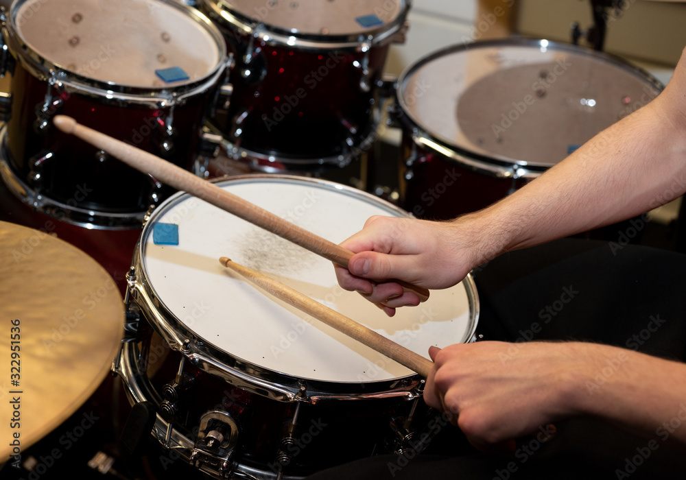 Closeup of a pair of hands with drumsticks playing a drum set. Closeup of a pair of hands with drumsticks playing a drum set.