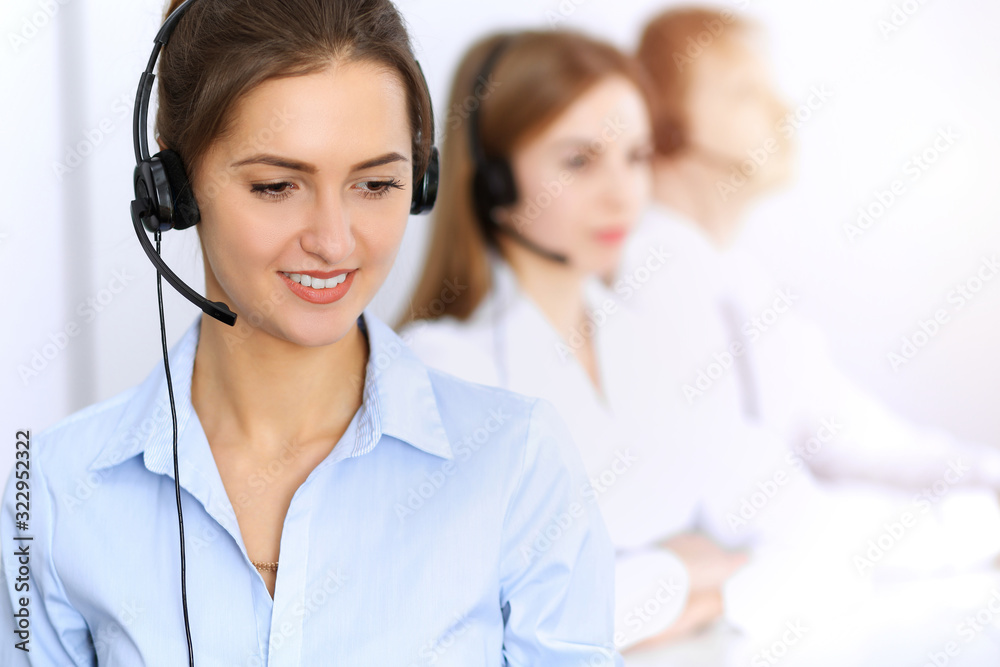 Call center. Focus on beautiful business woman using headset in sunny office Call center. Focus on beautiful business woman using headset in sunny office