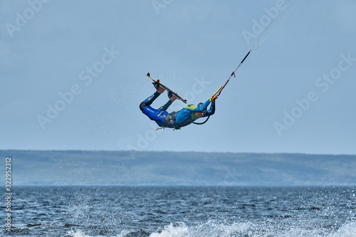 A male kiter slides on the surface of the water. Splashes of water fly apart.