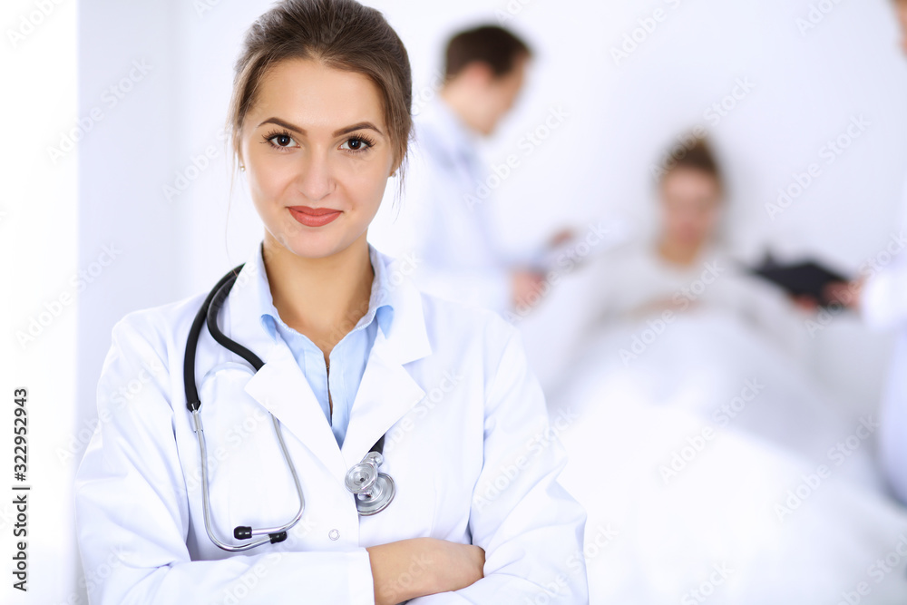 Female doctor smiling on the background with patient in the bed and two doctors Female doctor smiling on the background with patient in the bed and two doctors