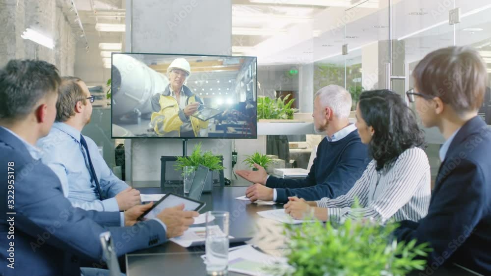 Diverse Group of Board Members, Executives and Management in the Meeting Room, Have Conference Video Call with Factory Chief Female Engineer, She Talks about Production Growth, Uses Tablet Computer