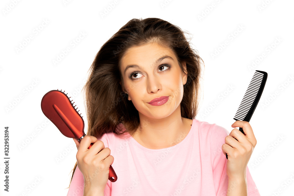A young woman with the messy hair holding comb and hair brush A young woman with the messy hair holding comb and hair brush
